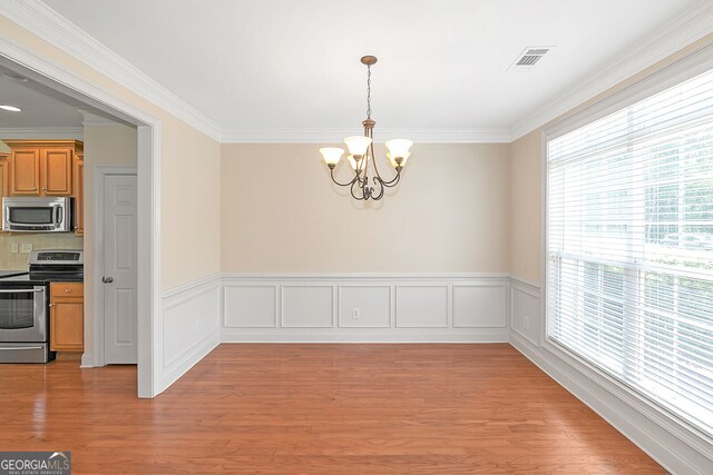 unfurnished dining area featuring a chandelier, crown molding, visible vents, and light wood finished floors