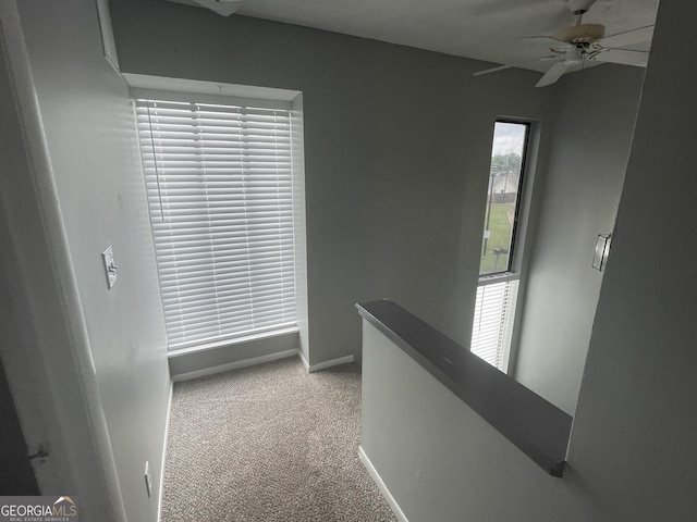 hall featuring baseboards, carpet flooring, and an upstairs landing