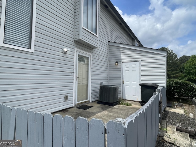 doorway to property featuring central air condition unit and fence
