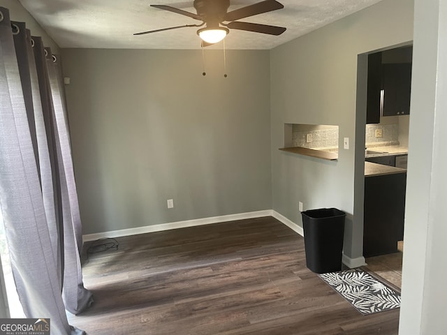 interior space with ceiling fan, a textured ceiling, baseboards, and dark wood-type flooring