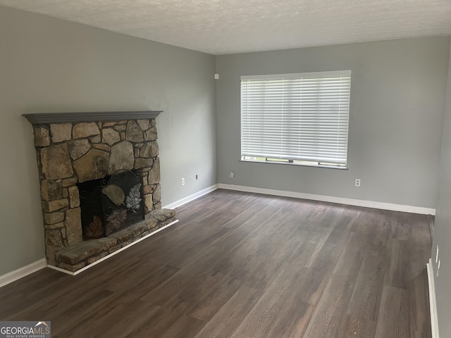 unfurnished living room featuring a textured ceiling, wood finished floors, baseboards, and a fireplace