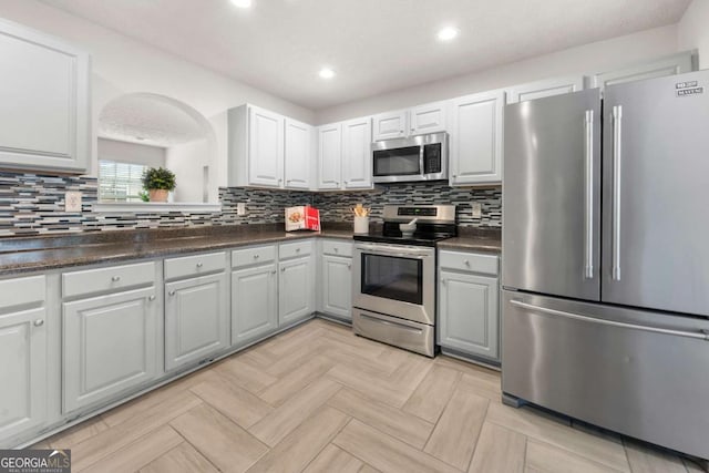 kitchen featuring dark countertops, stainless steel appliances, and tasteful backsplash