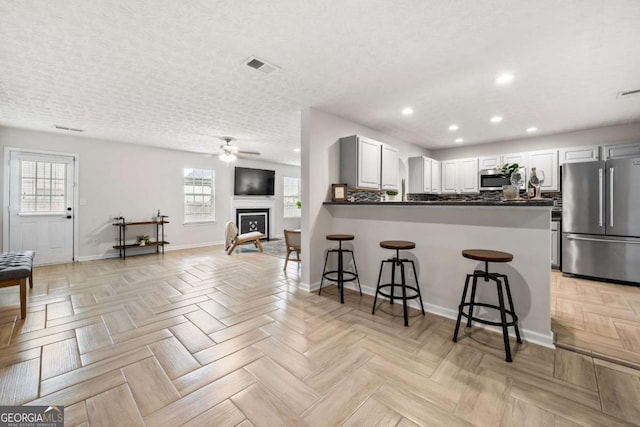 kitchen with visible vents, recessed lighting, ceiling fan, a kitchen bar, and appliances with stainless steel finishes
