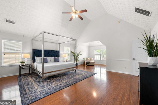 bedroom with baseboards, high vaulted ceiling, visible vents, and wood finished floors