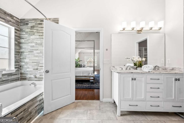 full bathroom featuring a bathtub, ensuite bath, a sink, tile patterned floors, and double vanity