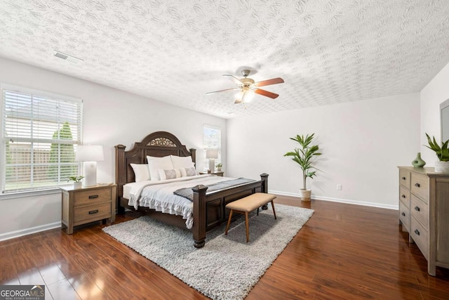 bedroom with baseboards, dark wood-style floors, visible vents, and a textured ceiling