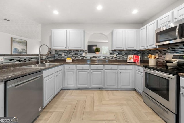 kitchen featuring a sink, dark countertops, backsplash, appliances with stainless steel finishes, and recessed lighting