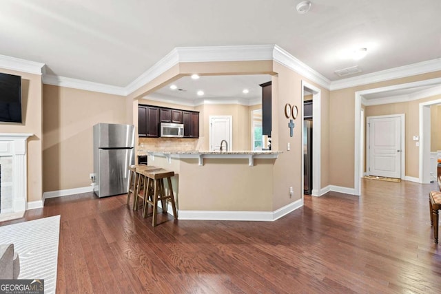 kitchen with light stone countertops, a breakfast bar area, dark wood finished floors, dark brown cabinetry, and stainless steel appliances