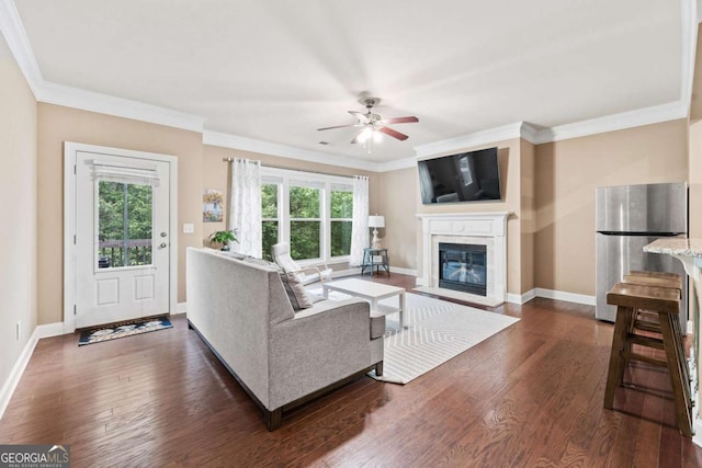 living area with baseboards, ornamental molding, dark wood finished floors, and ceiling fan