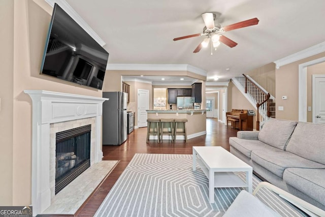 living room with ceiling fan, ornamental molding, stairs, and a high end fireplace