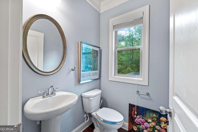 bathroom featuring crown molding, toilet, baseboards, and a sink