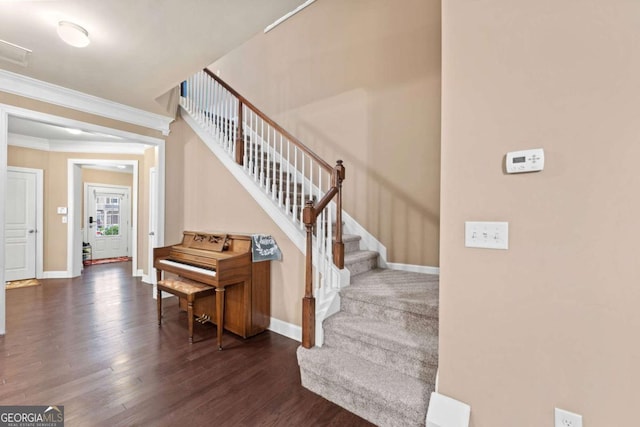 stairway with crown molding, wood finished floors, visible vents, and baseboards