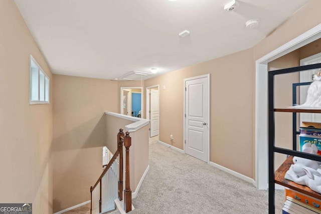 corridor with attic access, baseboards, carpet flooring, and an upstairs landing
