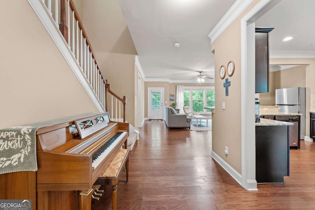 hallway featuring wood finished floors, baseboards, ornamental molding, and stairs