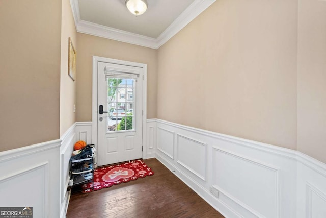 doorway with dark wood-style flooring, a decorative wall, crown molding, and a wainscoted wall