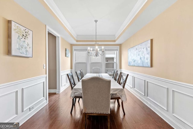 dining room with a chandelier, a raised ceiling, crown molding, and dark wood-type flooring