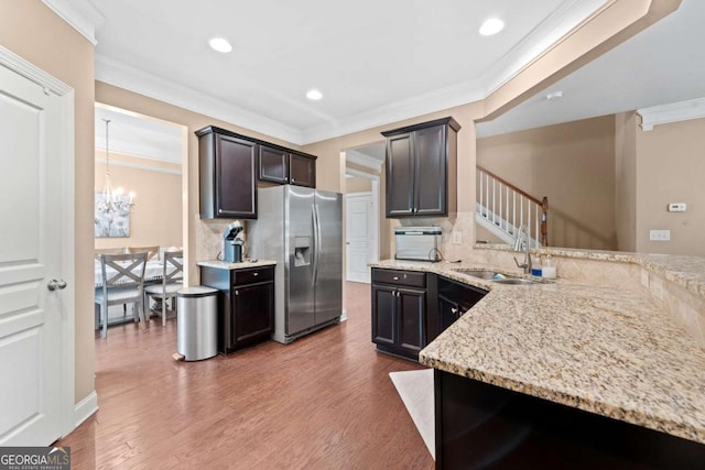 kitchen featuring ornamental molding, an inviting chandelier, decorative backsplash, light stone countertops, and stainless steel fridge with ice dispenser