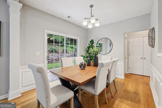 715 Alstonefield Dr, Alpharetta, GA 30004 - dining room with wainscoting, a decorative wall, a chandelier, light wood finished floors, and decorative columns