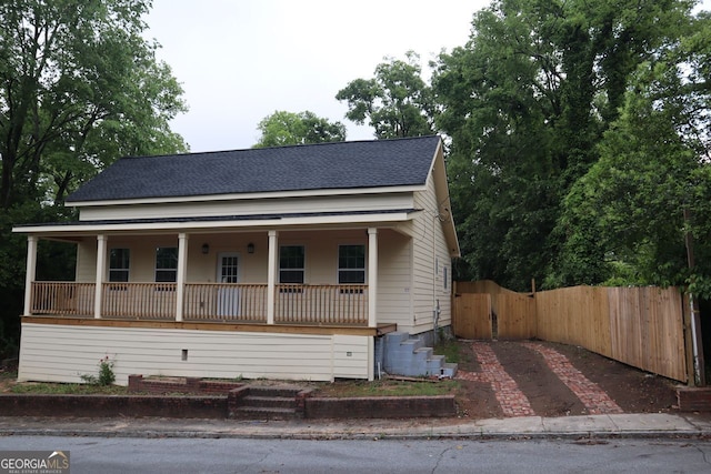 bungalow-style house featuring a shingled roof, a porch, a gate, and fence