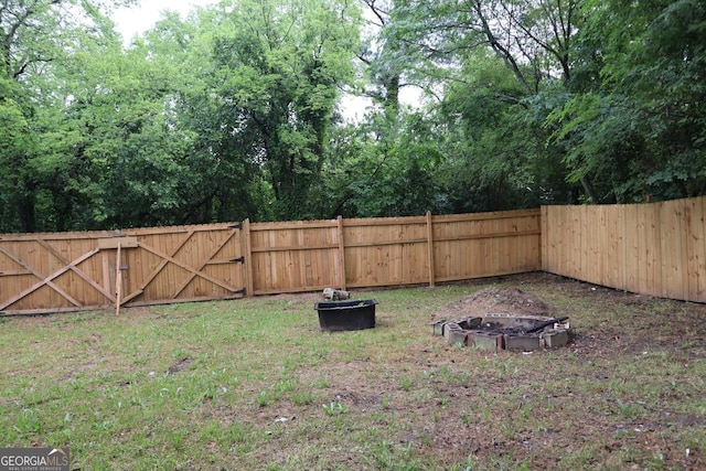 view of yard with a fenced backyard and a fire pit