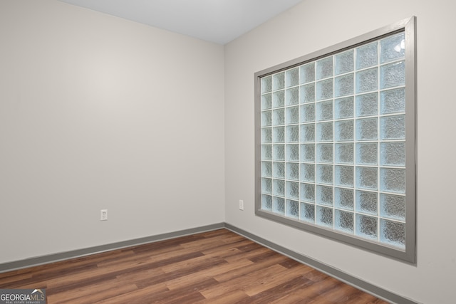 empty room with baseboards, dark wood-style flooring, and a wealth of natural light