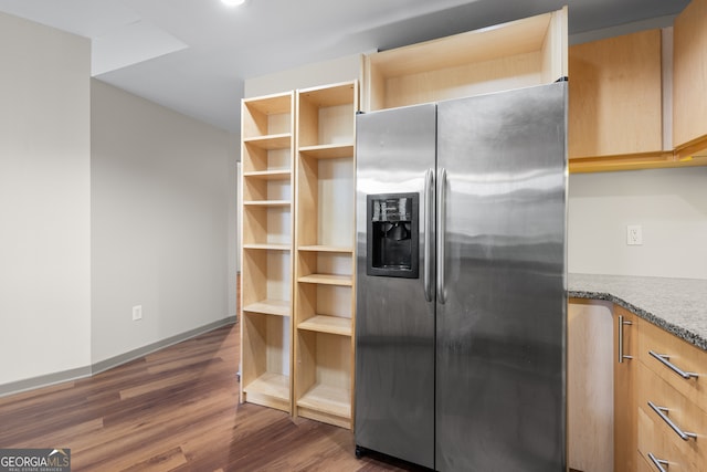 kitchen featuring stainless steel fridge, light brown cabinetry, baseboards, dark wood-style flooring, and light stone countertops