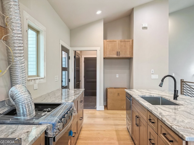 kitchen with light wood finished floors, a sink, stainless steel appliances, light stone countertops, and vaulted ceiling