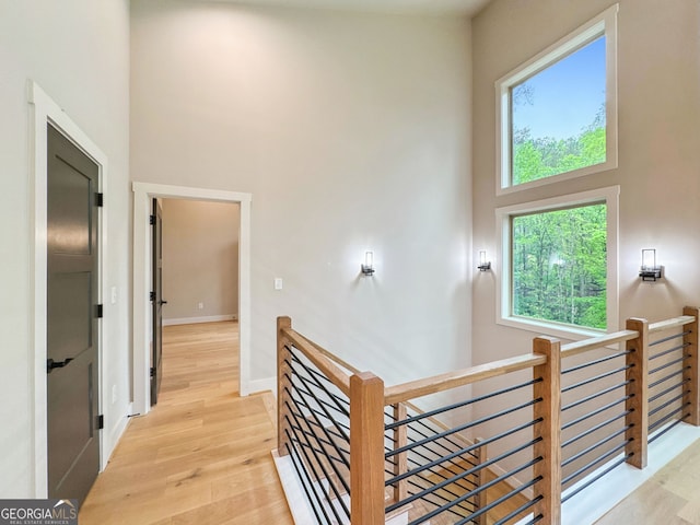 hallway with wood finished floors, an upstairs landing, baseboards, and a high ceiling