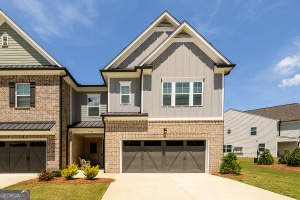 view of front facade with an attached garage, concrete driveway, board and batten siding, brick siding, and a standing seam roof