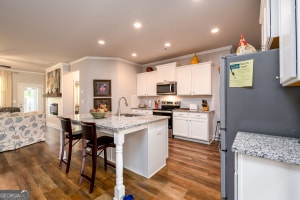 kitchen with a kitchen breakfast bar, white cabinets, crown molding, a center island with sink, and appliances with stainless steel finishes