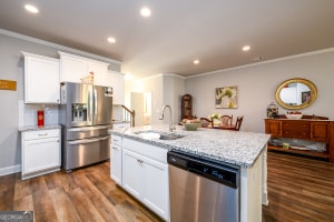 kitchen with crown molding, white cabinetry, stainless steel appliances, and a sink