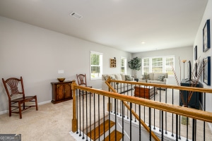 interior space with light colored carpet, a wealth of natural light, an upstairs landing, and baseboards