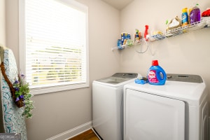 clothes washing area featuring baseboards, separate washer and dryer, laundry area, and wood finished floors