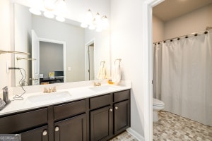 bathroom featuring double vanity, toilet, a shower with curtain, and a sink
