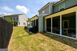 back of house featuring a sunroom, a yard, and fence