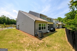 back of house featuring fence, cooling unit, and a lawn