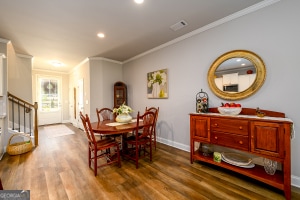 dining area with baseboards, crown molding, and wood finished floors