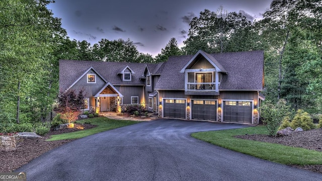 craftsman-style home with an attached garage, a shingled roof, stone siding, and driveway