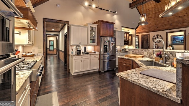 kitchen with a sink, light stone countertops, stainless steel refrigerator with ice dispenser, and high vaulted ceiling