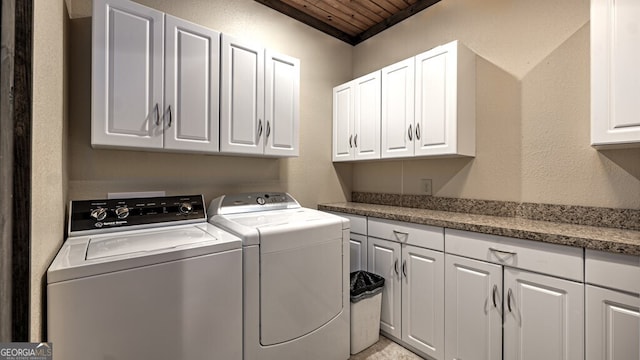 clothes washing area featuring cabinet space, wood ceiling, separate washer and dryer, and a textured wall
