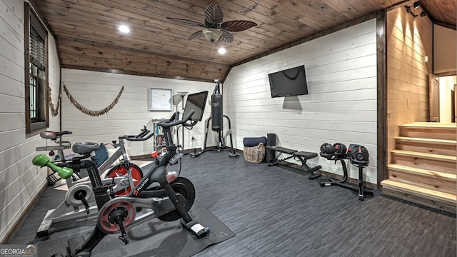 exercise room with wooden ceiling, wood walls, a ceiling fan, and wood finished floors