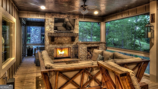 living area featuring a ceiling fan, a stone fireplace, hardwood / wood-style floors, and wooden ceiling