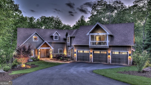 craftsman-style home featuring stone siding, a shingled roof, driveway, and an attached garage