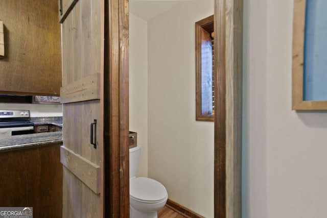 bathroom with toilet, wood finished floors, and baseboards