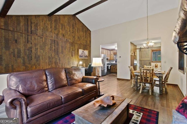 living area featuring wood finished floors, high vaulted ceiling, a notable chandelier, wood walls, and beamed ceiling