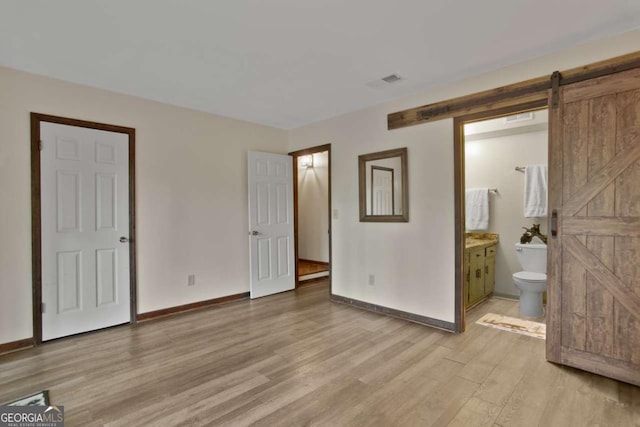200 Villa Rd Unit 128, Jasper, GA 30143 - unfurnished bedroom with a barn door, light wood-style floors, and ensuite bath