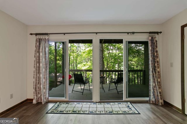 doorway to outside featuring baseboards, plenty of natural light, and wood finished floors