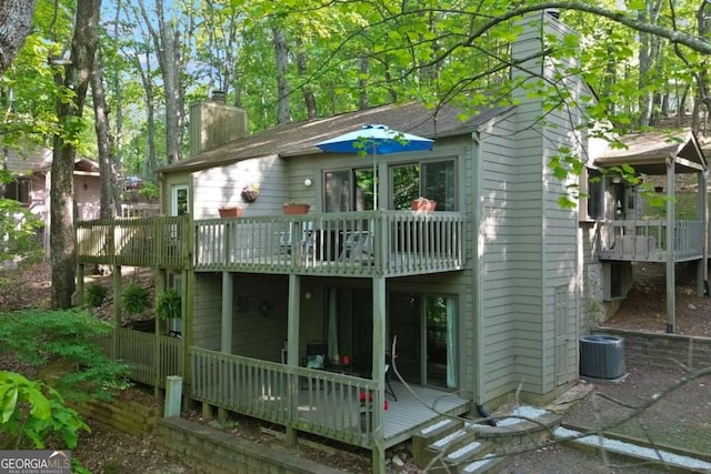 back of house with central AC unit, a chimney, a wooden deck, and a balcony