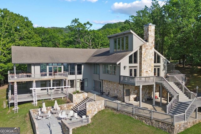 rear view of house featuring stone siding, a patio area, a chimney, and stairs