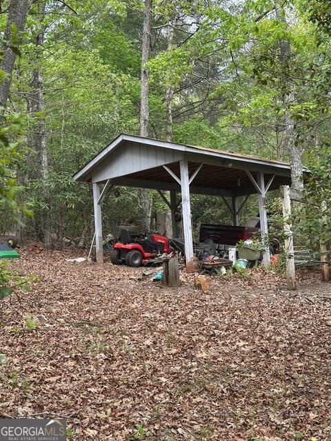 view of yard with a detached carport and a view of trees